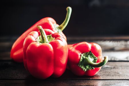 Sweet Red peppers on wooden background in studio photo with wated drops, after rainの写真素材