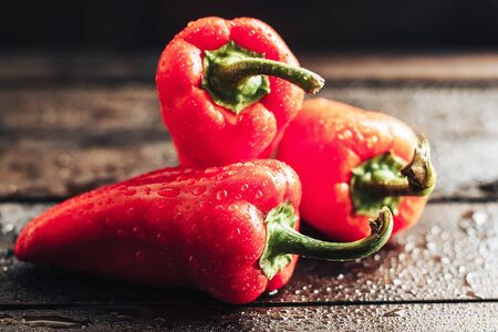 Three sweet peppers, wooden table background, sunlight, fresh food, healthy vegetarianの写真素材