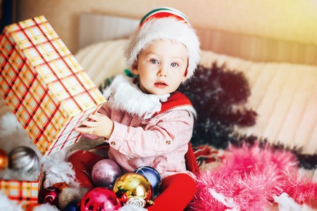 Baby first christmas. Beautiful little baby celebrates Christmas. New Year's holidays. Baby with santa hat with gift. Santa baby.の写真素材
