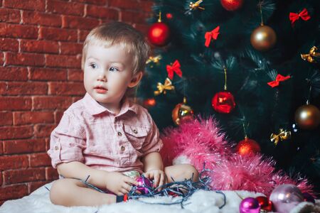 Cute baby with toys and Christmas tree on background. Holidays celebration conceptの写真素材