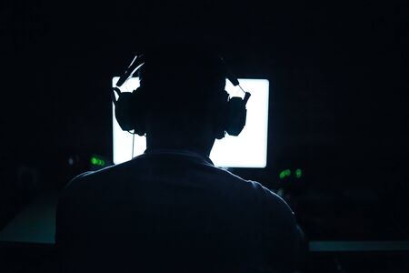 silhouette of playing man on computer in dark roomの写真素材