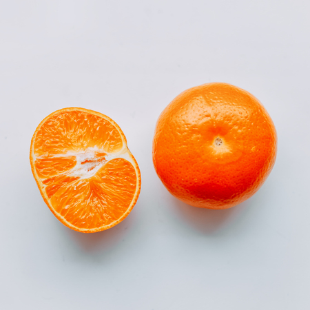 Fresh whole mandarin cut in half with leaves top viewの写真素材