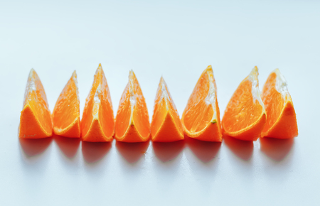 Line of fresh orange slices lie in line on white table, copy spaceの写真素材