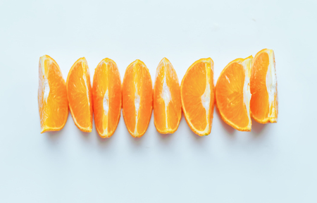 Line of fresh orange slices lie in line on white table, copy spaceの写真素材