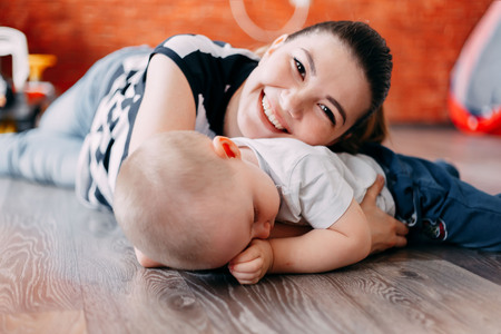 Joyful toddler on back of his mother, baby playing with motherの写真素材