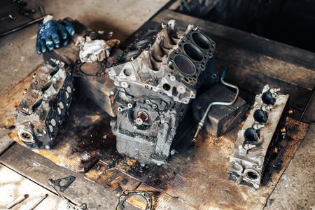 Disassembled car dirty engine close-up to engine parts and cylinder head at car garage