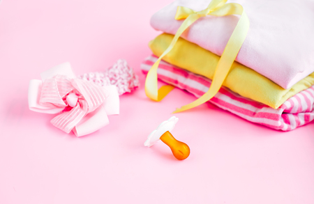Baby clothes and accessories on pink background, things and stuff for newborn baby girl, focus on pacifierの写真素材