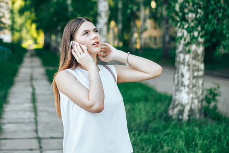 technology, lifestyle, communication and people concept - smiling young woman or teenage girl calling on smartphone on city streetの写真素材