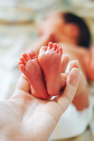 Baby feet in mother hands. Newborn Baby's feet on female Heart Shaped hands closeup. Mom and her Child. Happy Family concept. Beautiful conceptual photo of Maternity.の写真素材