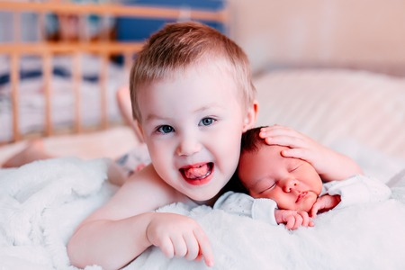A little boy is playing with his newborn baby sister. Concept of happy family.の写真素材