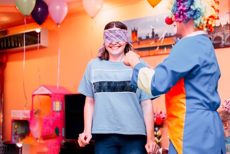 young woman play blind man's buff with clown on children's party, birthday holidayの写真素材