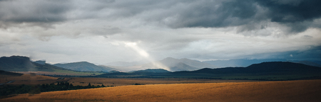 ray of light makes its way in the clouds, landscape road and field, cloudy sky. long bannerの写真素材