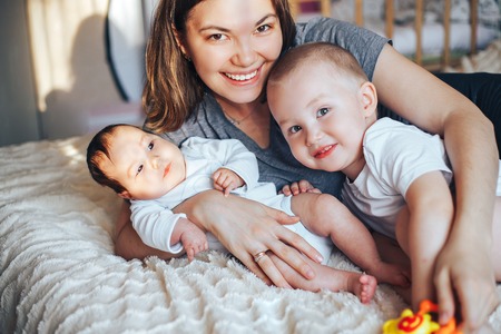 happy family mother and two children, son and daughter in bed playingの写真素材
