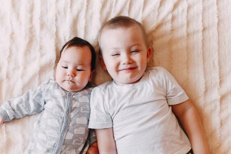 little baby girl sitting on brother back yawn playingの写真素材