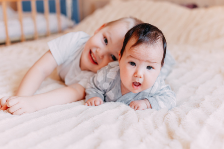 elder brother is playing with the newborn. cute boy lovingly playing with his baby sister. the concept of love and friendship between older and younger siblingsの写真素材