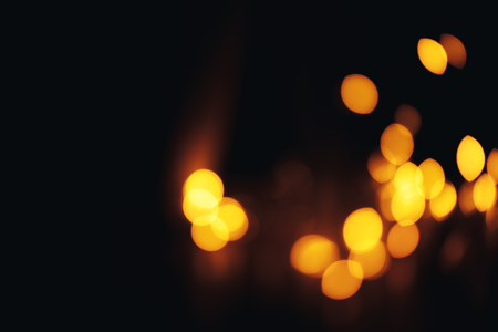 Blurred yellow bokeh with small drops on black background with copy space for text, texture, abstractの写真素材