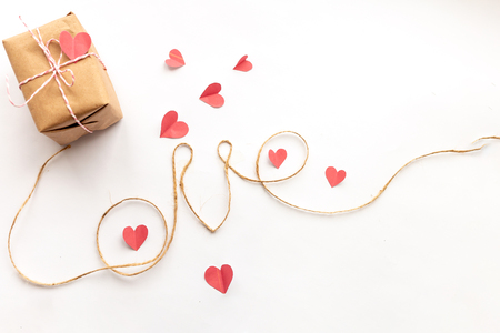 paper gift box with pink bow and paper hearts on white background, jute rope, love letters, top viewの写真素材
