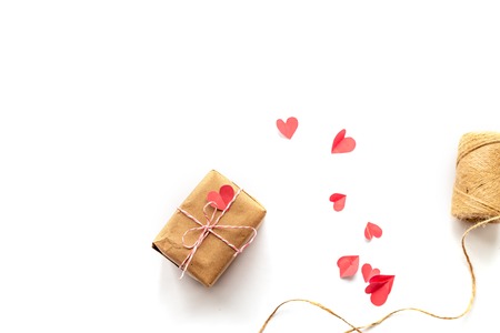 Inventory for gift packaging, top view. Minimal flat lay arrangement of box wrapped in brown kraft paper, jute rope on white background.    paper hearts aroundの写真素材
