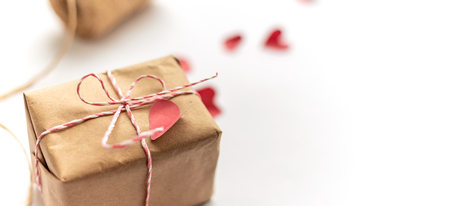 Packages wrapped in kraft paper tied with jute on whte background, focused on gift, selected focus red small paper heartsの写真素材