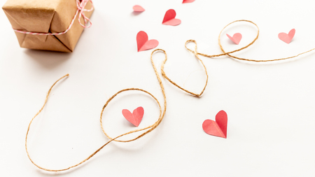 paper gift box with pink bow and paper hearts on white background, jute rope, love letters, top view copy spaceの写真素材