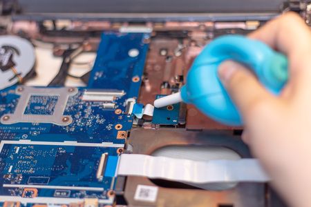 Cleaning computer with blower pump. Blowing debris from under the buttons on the keyboard with a...