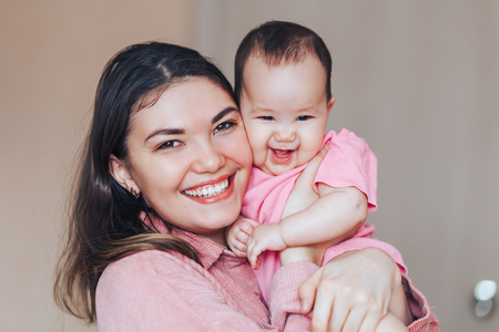 Mother and baby in pink clothes playing and laughing. A happy family mothers dayの写真素材