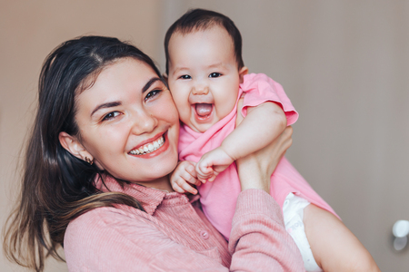 Mother and baby in pink clothes playing and laughing. A happy family mothers dayの写真素材