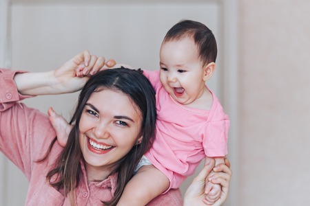 Mother and baby in pink clothes playing and laughing. A happy family mothers dayの写真素材
