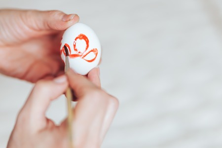 Hands painting modern style easter eggs with red green paint selected focusの写真素材