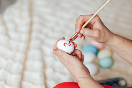 Hands painting modern style easter eggs with red green paint selected focusの写真素材