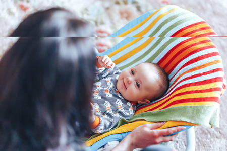 very beautiful nice blue eyed Baby child relaxing on a sunbed or a deck chair colored bouncer at homeの写真素材