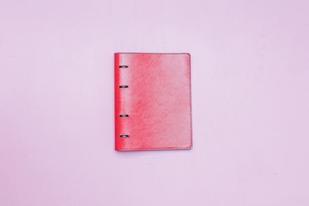 Notepad in the center on pink background flatlay copyspace.