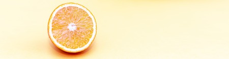 One circle slice of fresh ripe orange with pulp and peel on yellow and pink background. Top view....