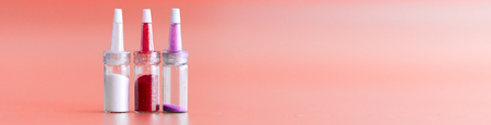 Bottles with multi-colored spangles and colored fillings for decoration, festive decoration on pink...