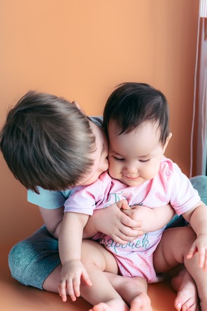 happy little brother playing hugs his sister baby, boy and girl embraces kisses, concept love and parenting.の写真素材