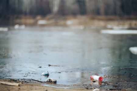 Abandoned empty pink plastic bottle and blue can garbage at the river bank conservancy pollution.の写真素材