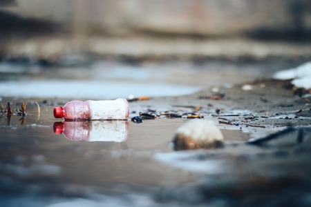 Abandoned empty pink plastic bottle garbage at the river bank conservancy pollution.の写真素材