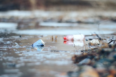 Abandoned empty pink plastic bottle and blue can garbage at the river bank conservancy pollution.の写真素材