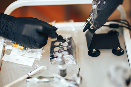 woman prepare instruments for permanent makeup to work pigment drop to palette.の写真素材