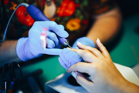 hardware manicure Manicurist is applying electric nail file drill to manicure on female fingers. saw nails. selected focusの写真素材