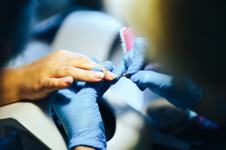 hardware manicure Manicurist is applying electric nail file drill to manicure on female fingers. saw nails. selected focusの写真素材