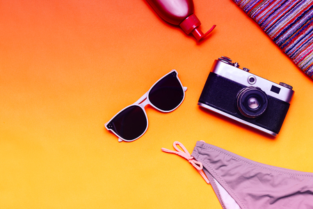 Flat lay summer accessories on yellow background with swimsuit, camera and sunglasses. Top view travel or vacation concept. Summer background. toned duocolour, purpleの写真素材