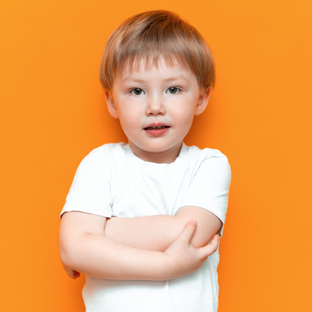 cheerful little boy child standing isolated over yellow background. Looking camera. with blonde hair mixed race central Asian and german.の写真素材
