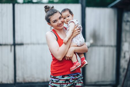 Beautiful Mother And Baby outdoors on the yard of house. Beauty Mum and her baby Child one year old playing in yard together. Mom and Baby.の写真素材