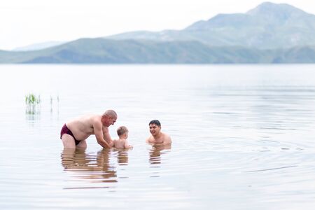 child with his grandfather and father play and swin in sea, summer time.の写真素材