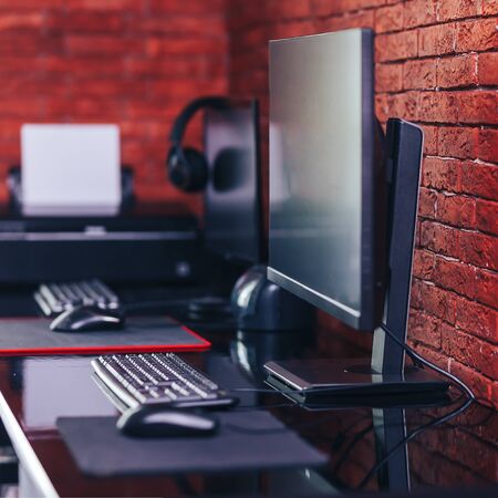 Two computer monitors with black screen on a desk, one workplace on table for two people.の写真素材