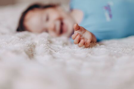 Baby girl or boy crawling on bed in white sheets, looking at the camera and reach to mother.の写真素材