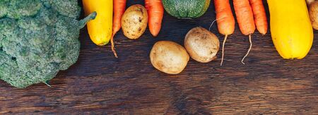 long banner with frame of Vegetables still life in wooden background with copy space top view flatlay broccoli yellow squash potatoes carrots zucchini.の写真素材