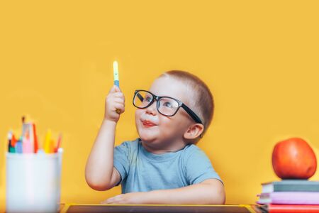 Little boy painting and doing homeworks on his desk having an idea, inspiration concept. back to school on yellow background.の写真素材