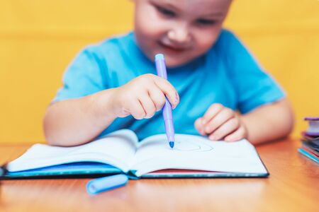 Little boy painting and doing homeworks on his desk, inspiration concept. back to school on yellow...